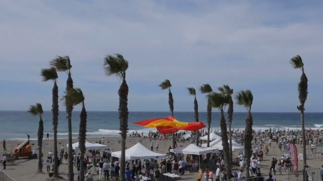 Una playa con carpas y público durante un simulacro de salvamento